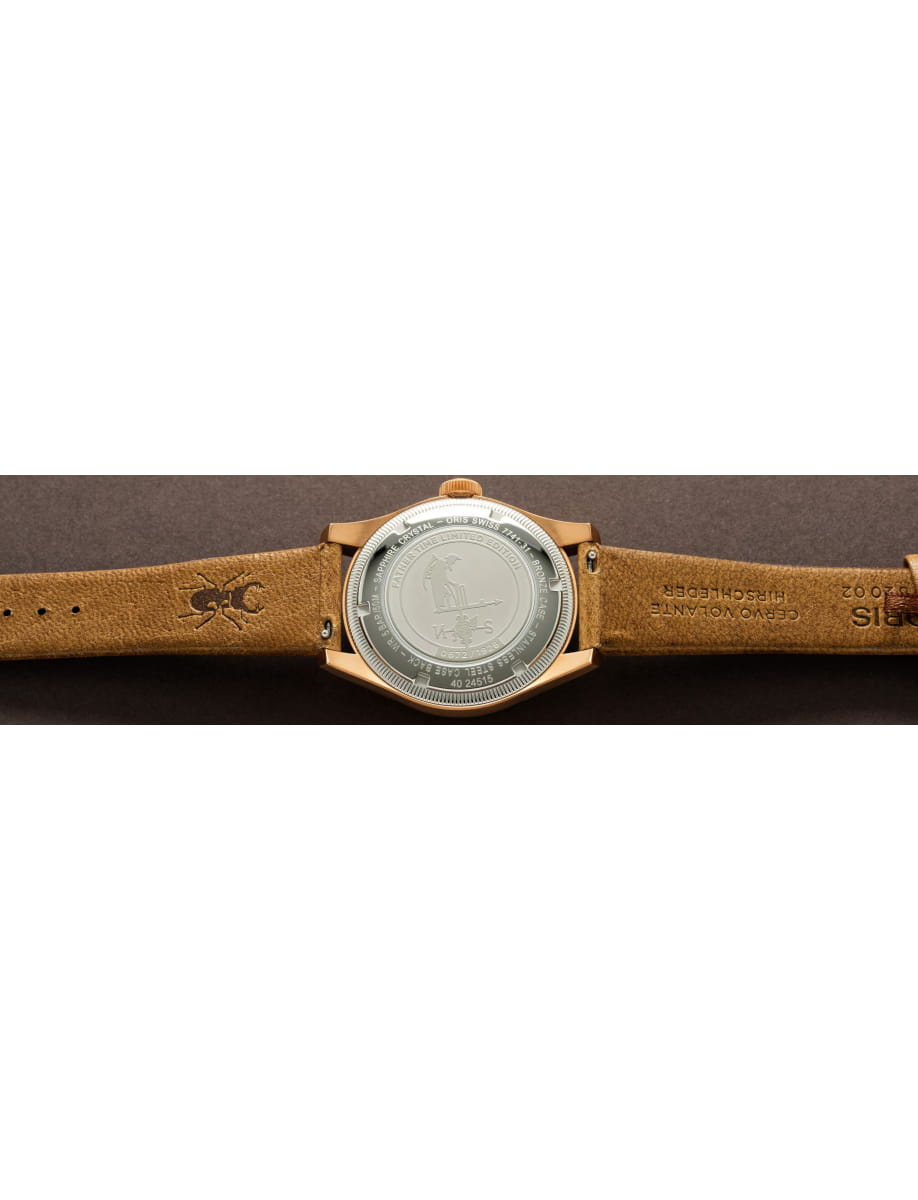Close-up of a brown leather strap watch with a silver case back facing up.