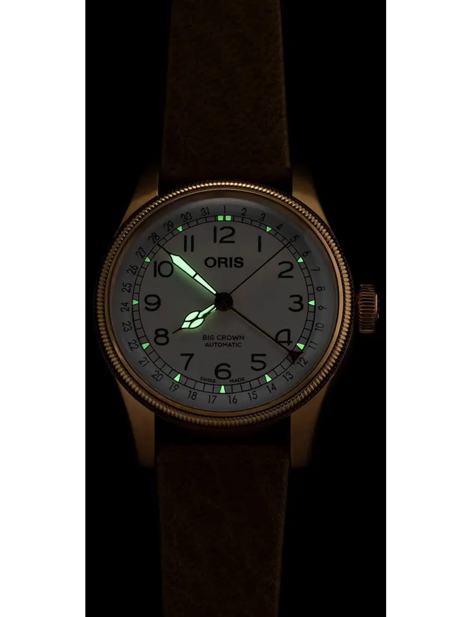 Oris Big Crown Automatic wristwatch with a white dial, luminous green hands, and a dark leather strap photographed in low light.
