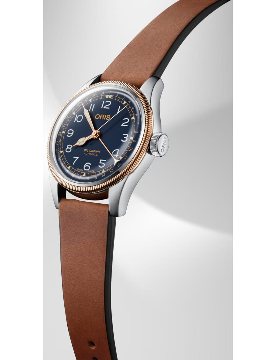 Close-up of an Oris Big Crown automatic wristwatch with a blue dial, rose-gold bezel, and brown leather strap viewed at an angle.