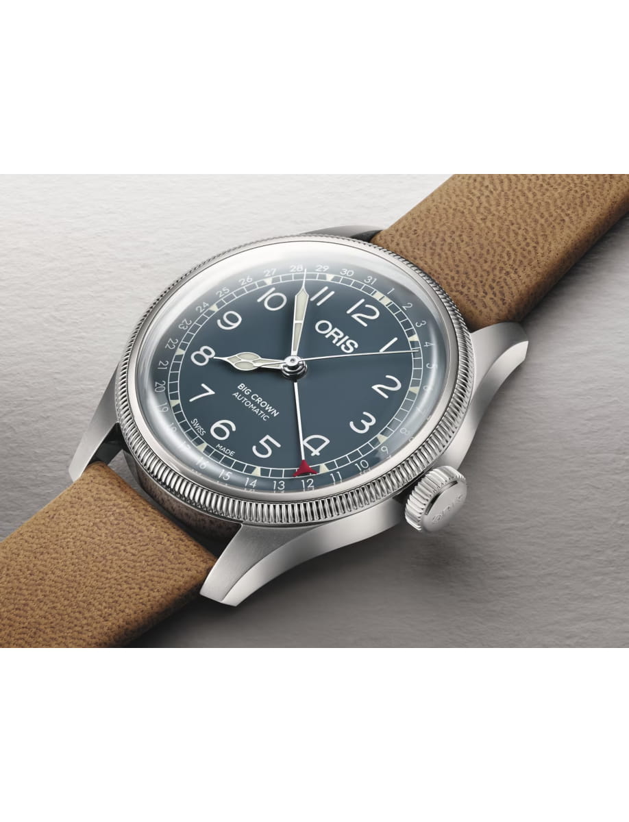 Blue-dial Oris wristwatch with a brown leather strap and knurled bezel, showing 'ORIS' and 'BIG CROWN AUTOMATIC' on the face.