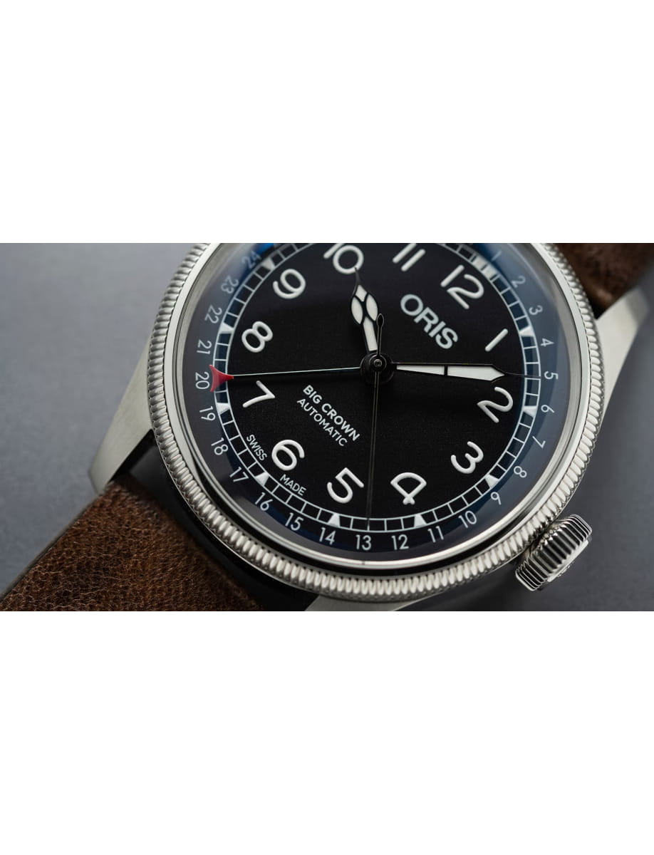 Close-up of an Oris Big Crown Automatic wristwatch with a black dial, white numerals, and a brown leather strap.