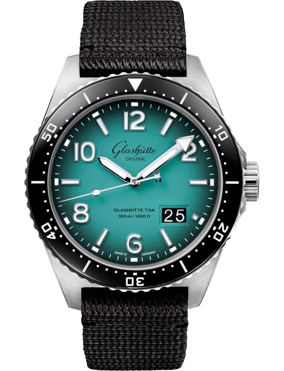 Wristwatch with teal dial, white numerals, black rotating bezel, stainless steel case, and black fabric strap; date window shows 25 at 4 o'clock.