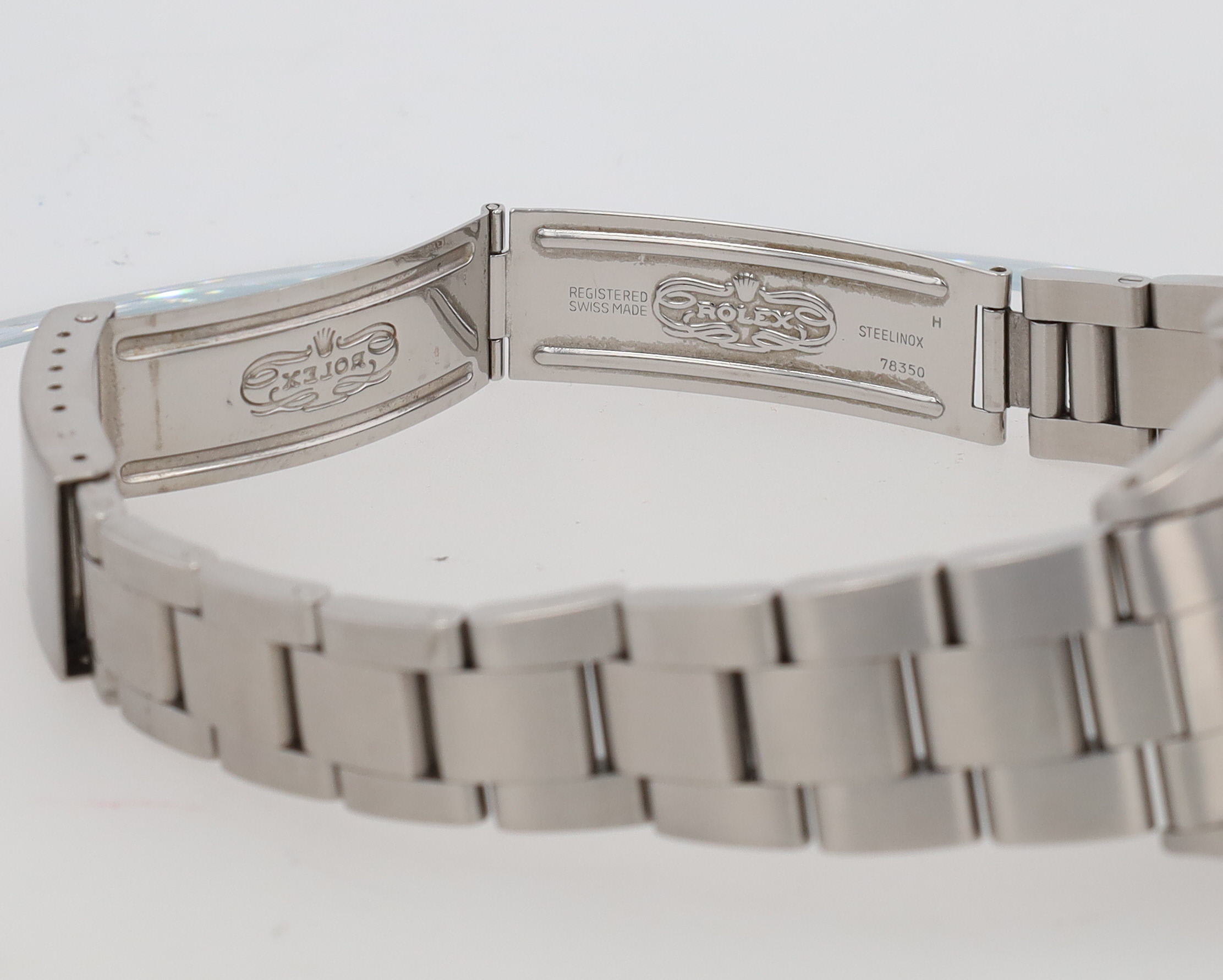 Close-up of a stainless steel Rolex bracelet clasp with the Rolex logo and 'Registered Swiss Made' engraving, 78350 visible.