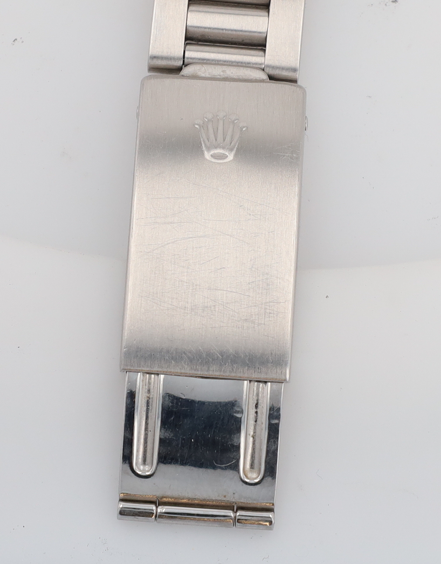 Close-up of a stainless steel Rolex watch bracelet clasp with the Rolex crown logo embossed on the surface