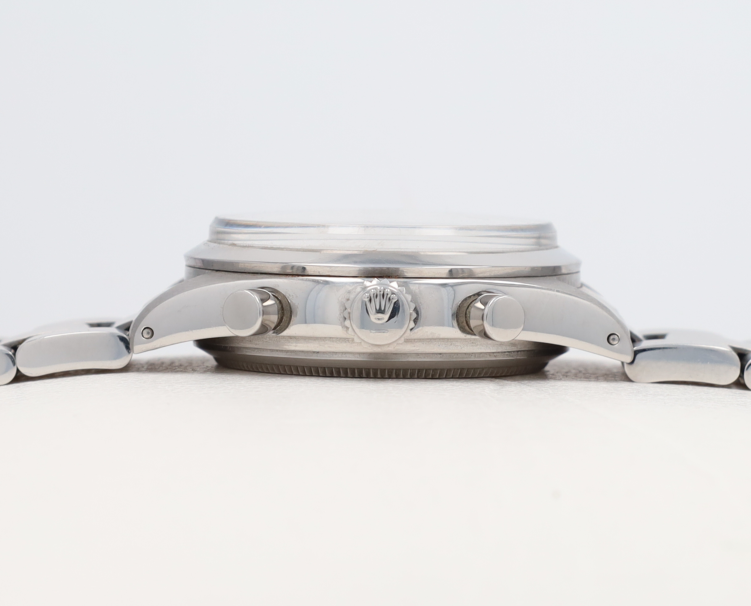 Close-up of a silver watch crown and case on a white background, showing metallic details and textures.