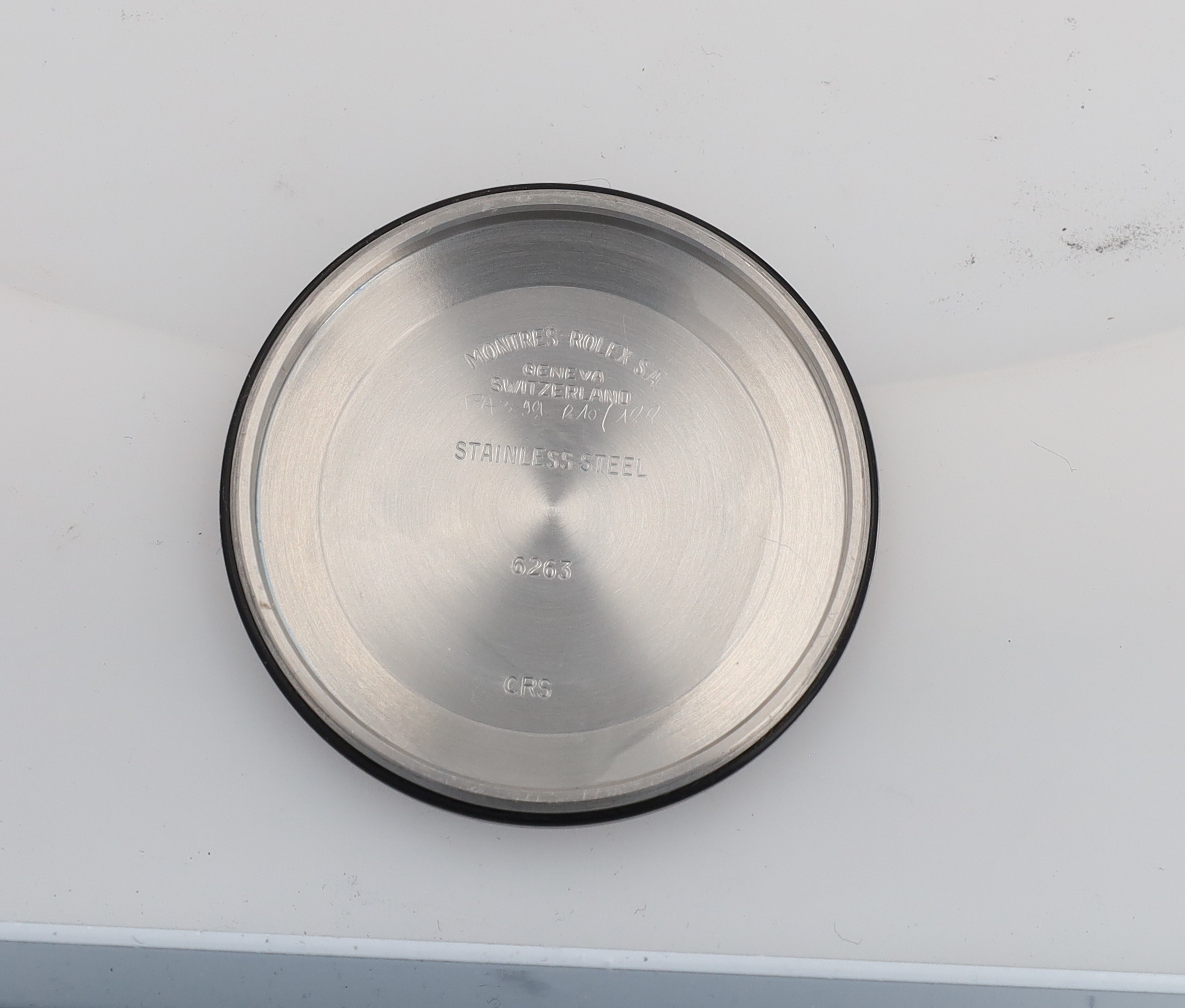 Close-up of a brushed stainless steel watch case back with engravings including Geneva, Switzerland, and 'STAINLESS STEEL'.
