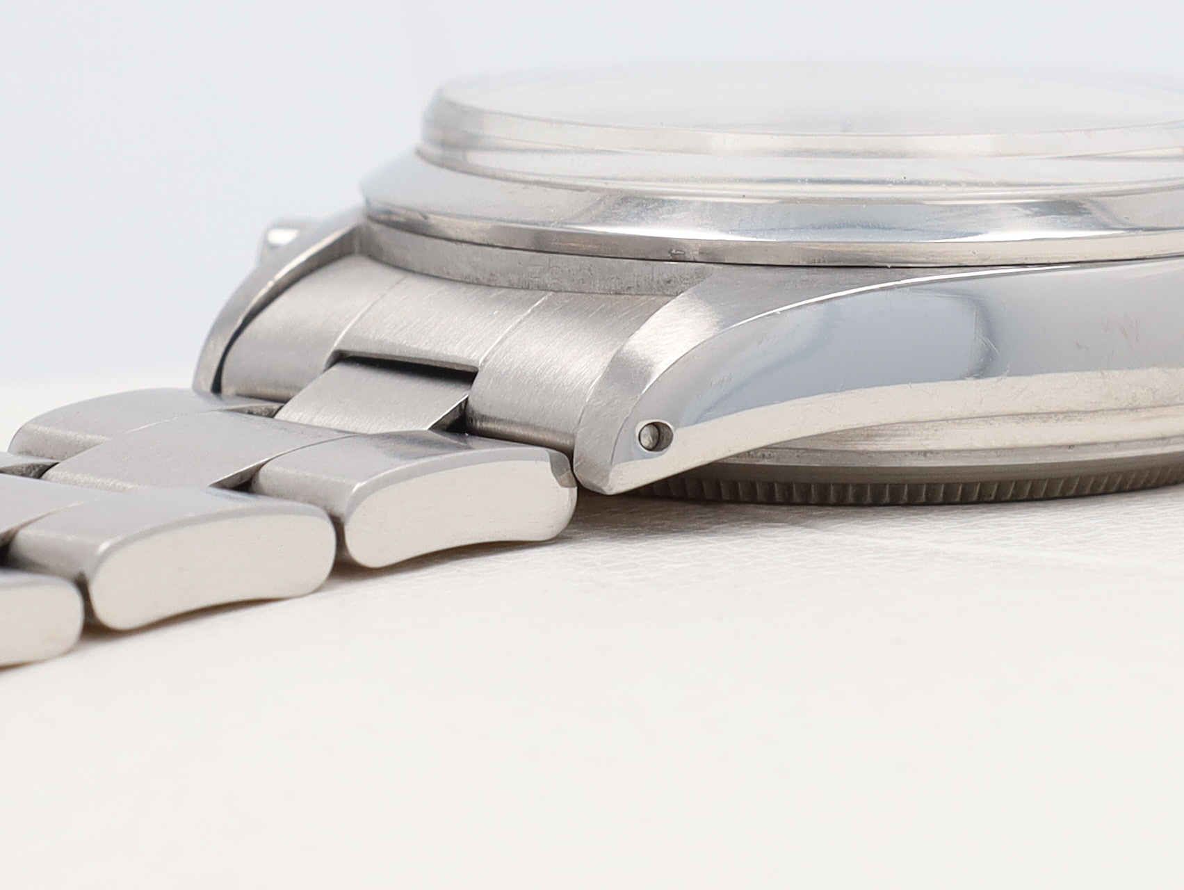 Close-up of a silver stainless steel wristwatch showing the brushed metal links and hinge at the band.