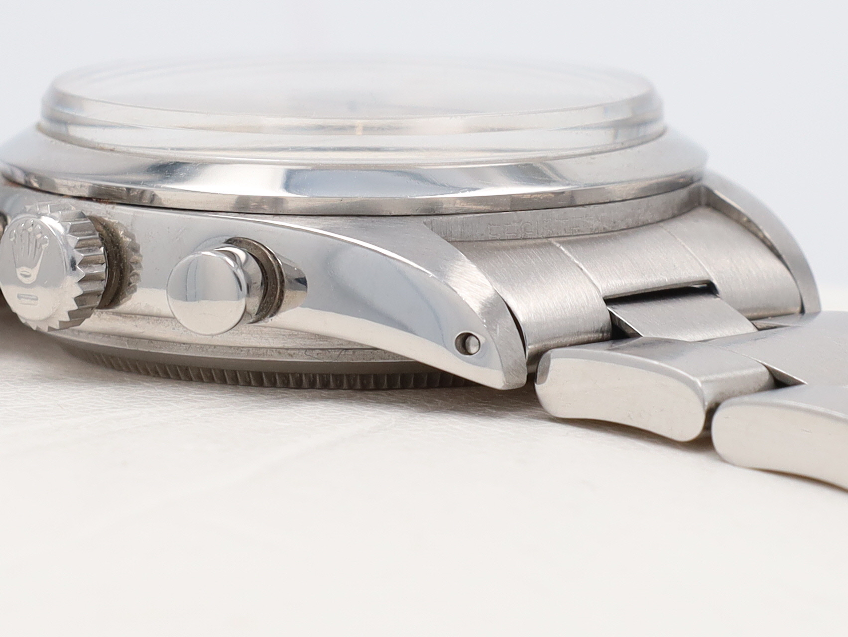 Close-up of a stainless steel wristwatch crown and pushers on a metal bracelet.