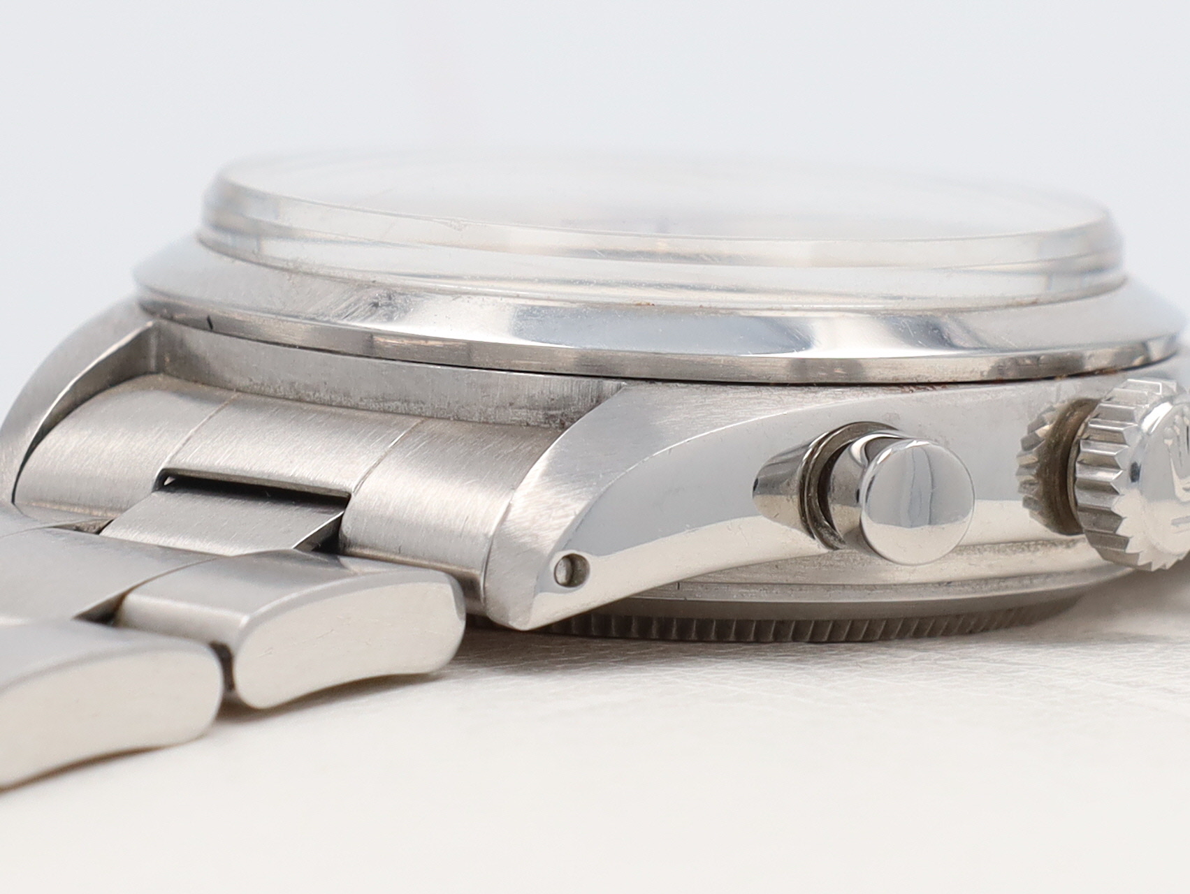 Close-up of a stainless steel wristwatch, showing the crown and brushed metal bracelet from the side.
