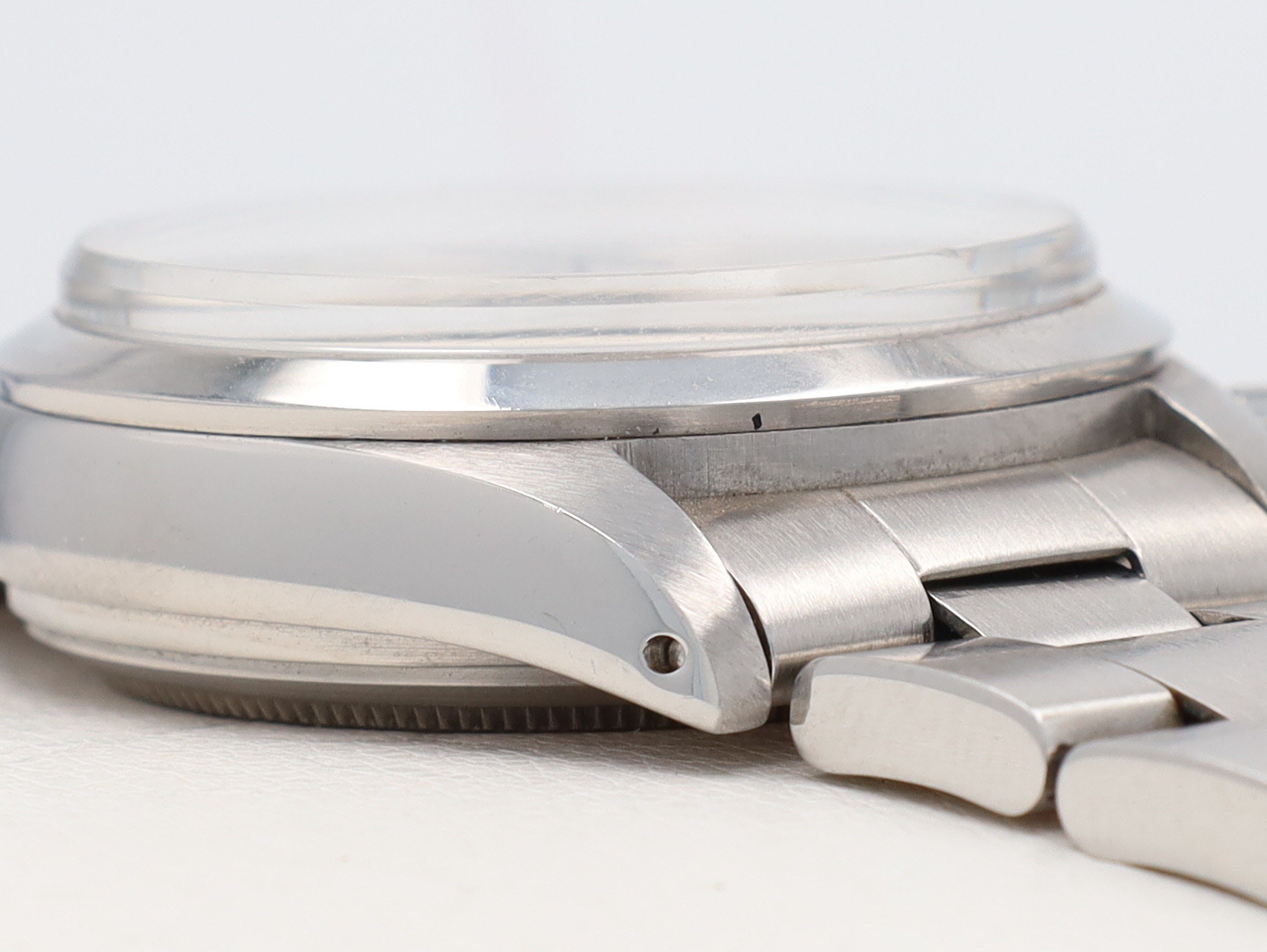Close-up of a silver metal wristwatch with a domed crystal and linked bracelet