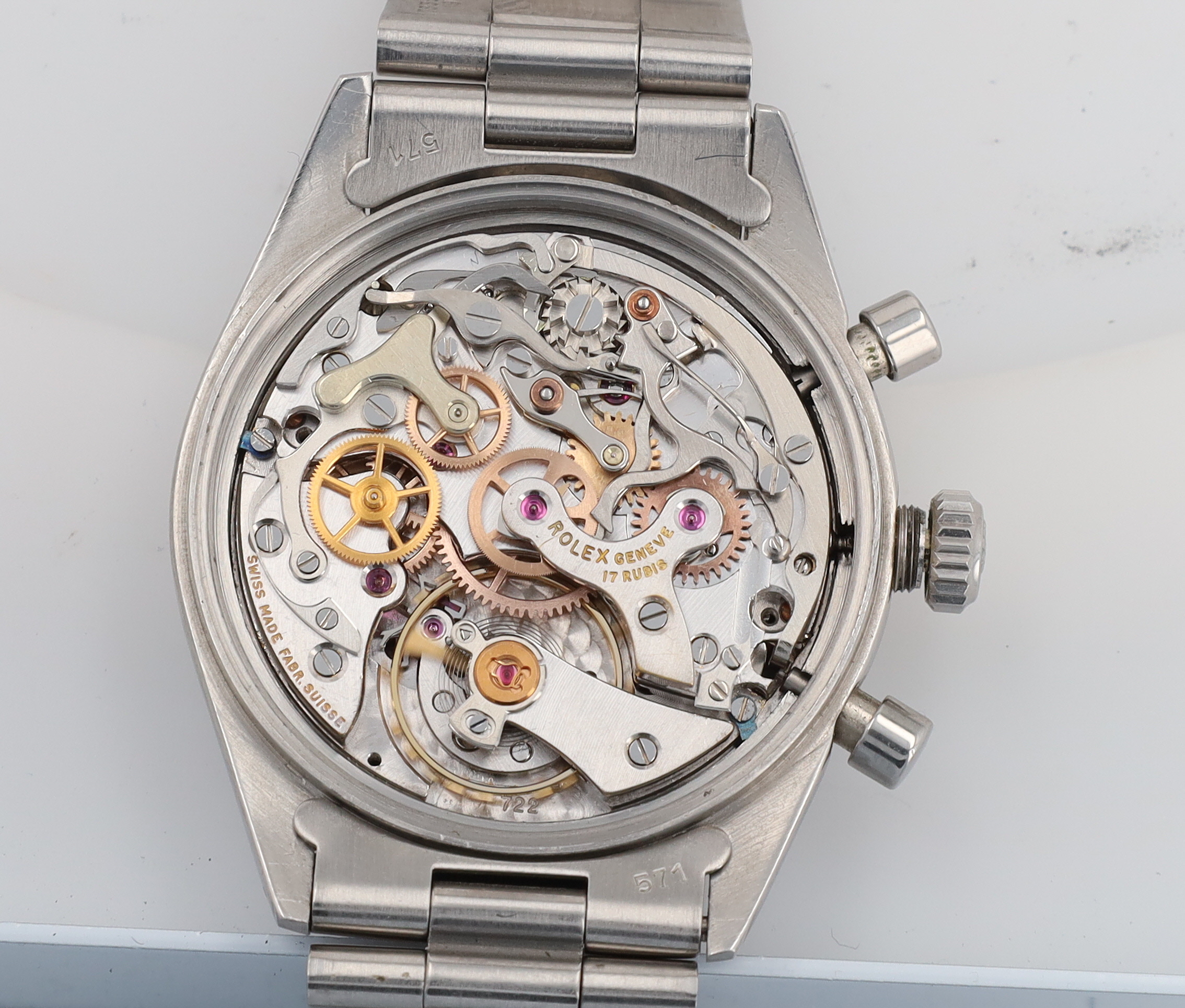 Close-up of a stainless steel watch with its case back removed, exposing intricate gears and components in the movement.