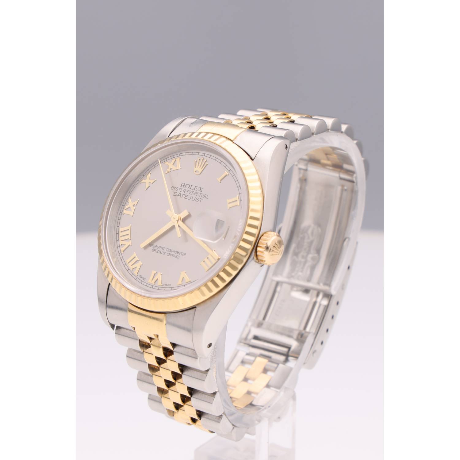 Two-tone Rolex Datejust wristwatch with gold Roman numerals and fluted bezel, angled against a gray backdrop.
