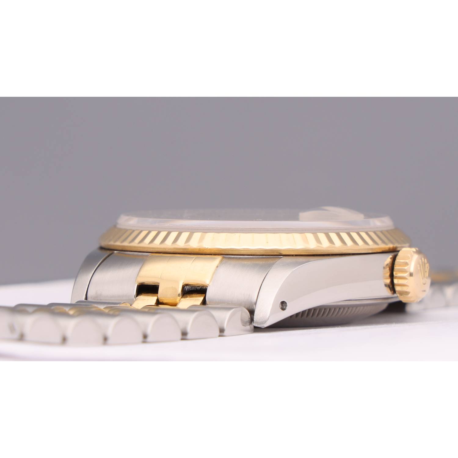Close-up side view of a two-tone gold and silver wristwatch resting on a surface.