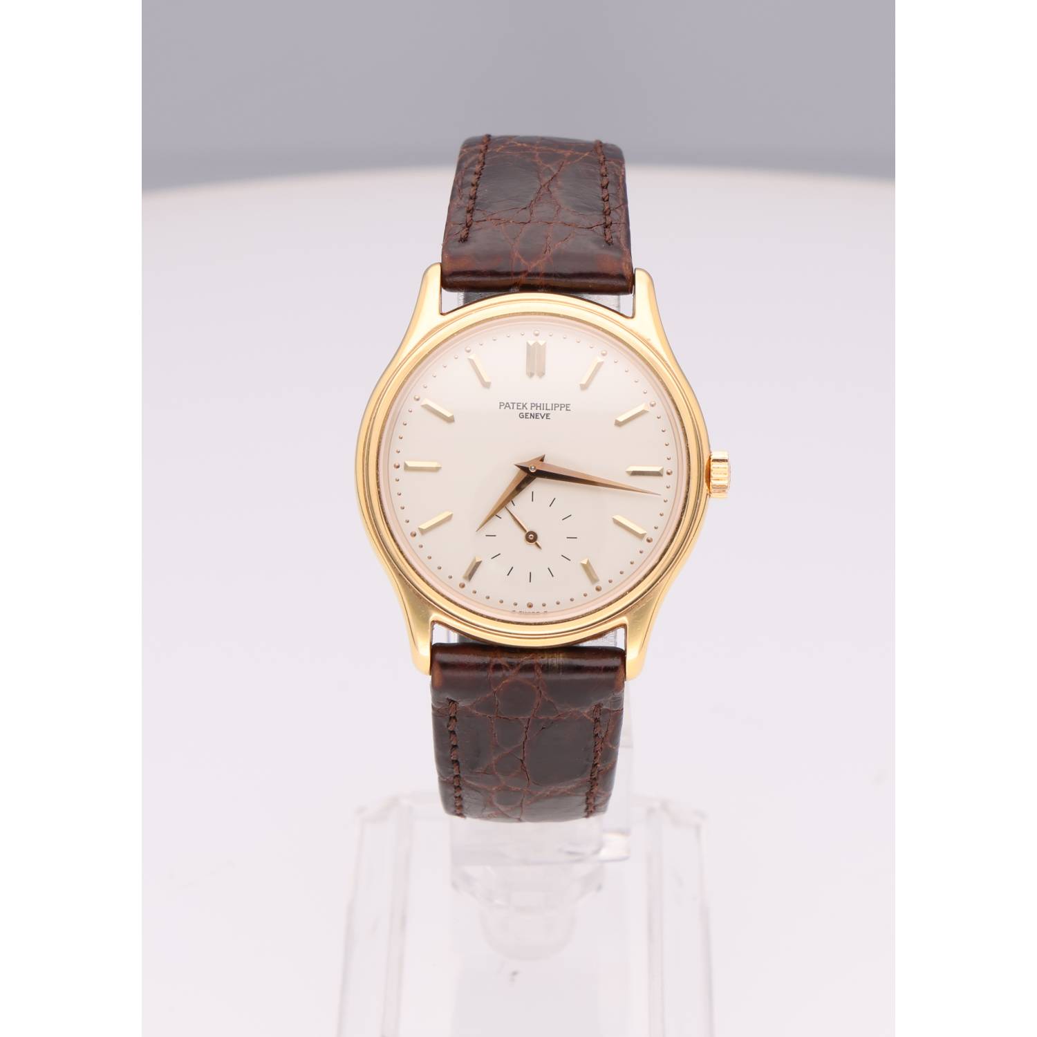 Gold watch with a cream dial and brown leather strap (Patek Philippe), front view on display.