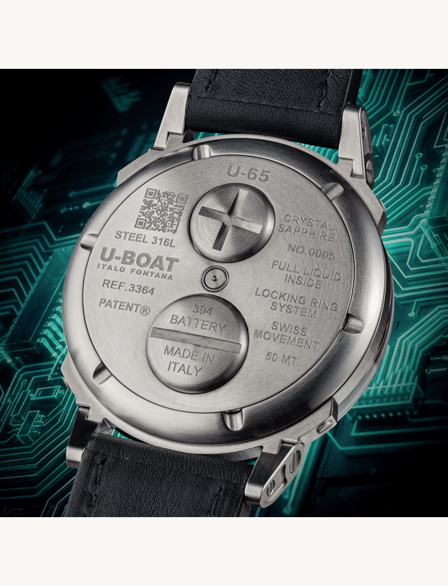 Back of a metal wristwatch with engraved details including U-BOAT ITALO FONTANA, 'MADE IN ITALY', and a central screw cap against a techy circuit-board backdrop.