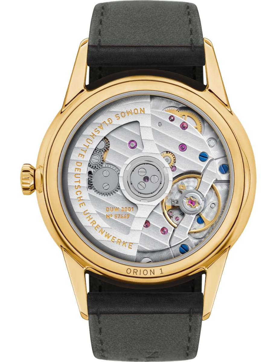 Gold wristwatch with a transparent case back showing intricate mechanical movement and gears outside.