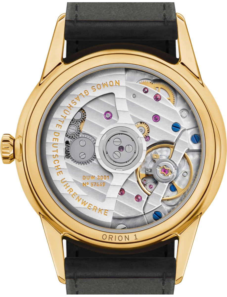 Gold wristwatch with transparent caseback showing intricate mechanical movement and gears; engravings read 'Orion 1' and 'DUW 3001' on the rotor.
