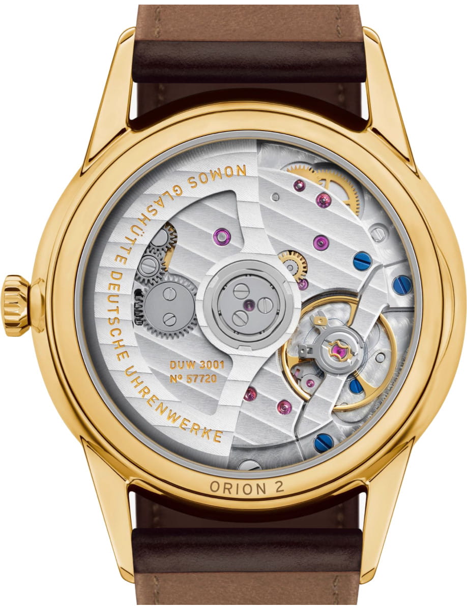 Gold wristwatch with a see-through back showing intricate mechanical movement and gears, brown leather strap.