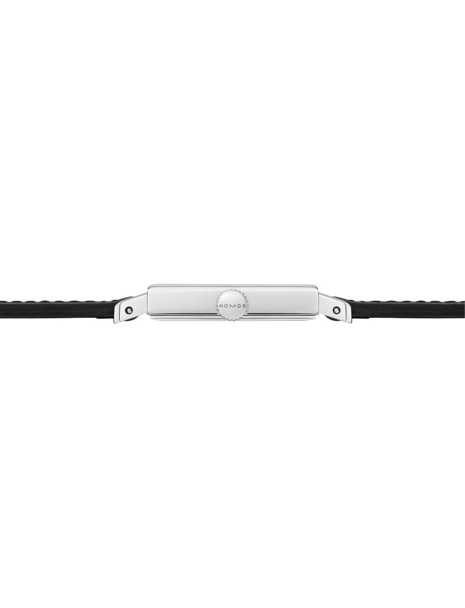 Close-up of a Nomos watch crown on a silver case with a black leather strap on either side