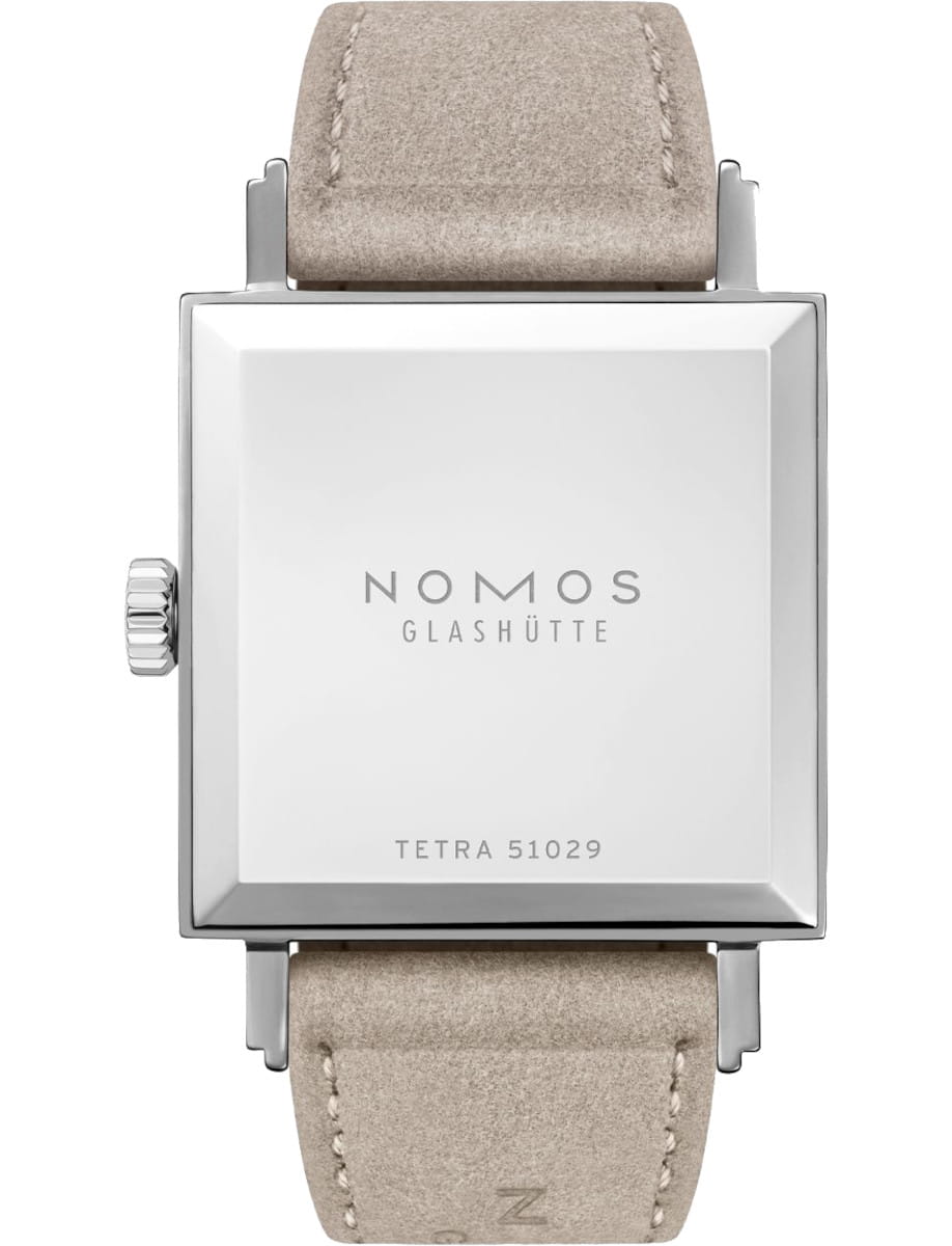 Square silver watch case back with NOMOS Glashütte branding and beige suede strap visible (model Tetra 51029).