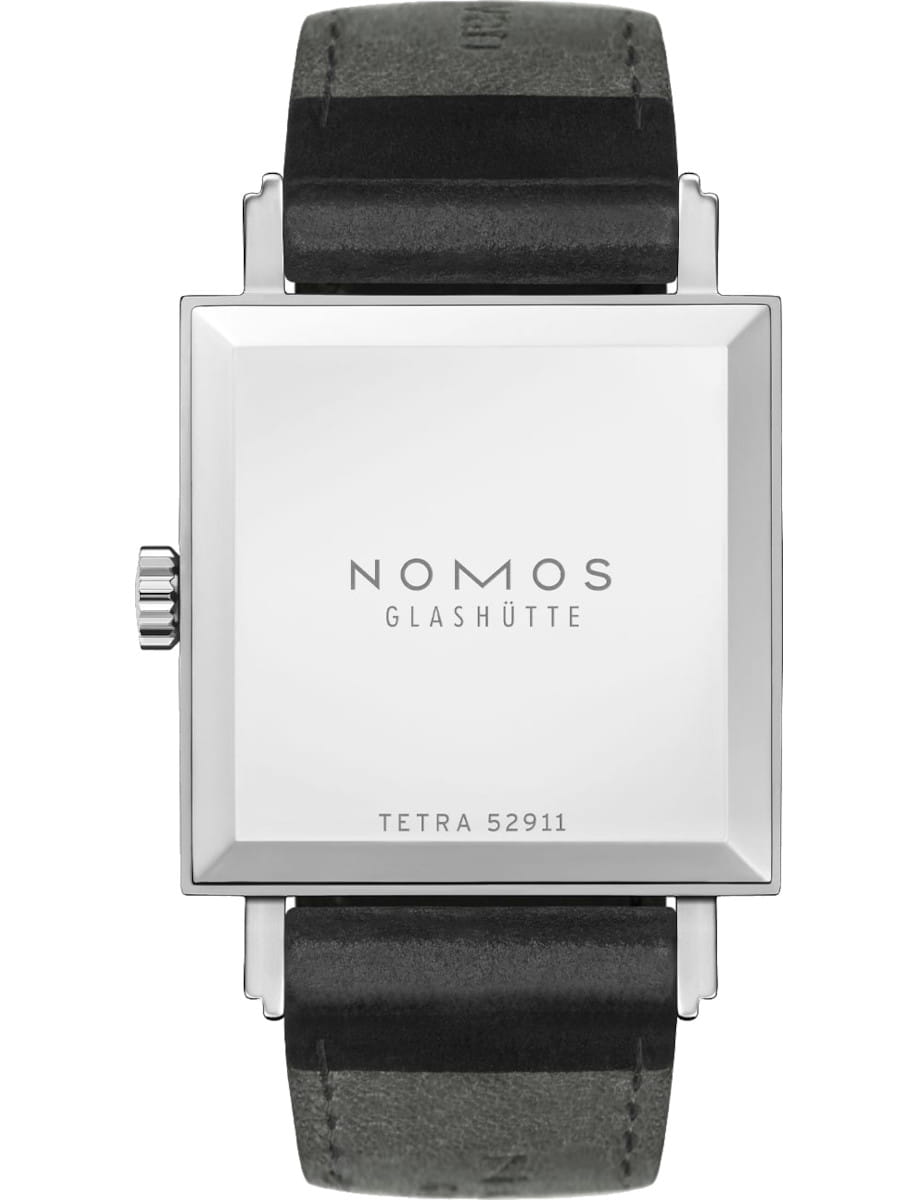 Back view of a square NOMOS Tetra watch with a silver case and black leather strap, showing the brand and model on the case back.