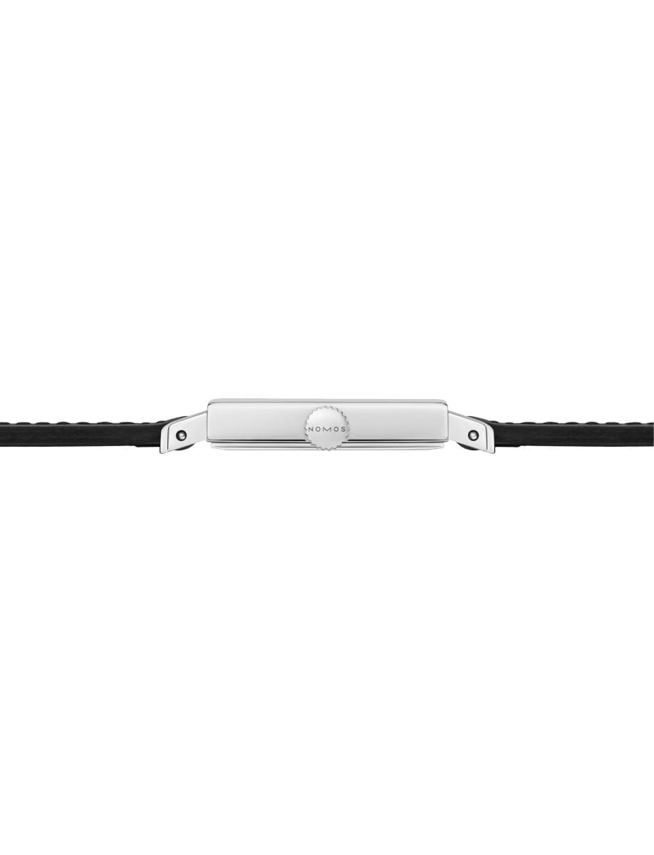 Close-up of a silver watch crown with the Nomos logo, centered between black straps against a white background.
