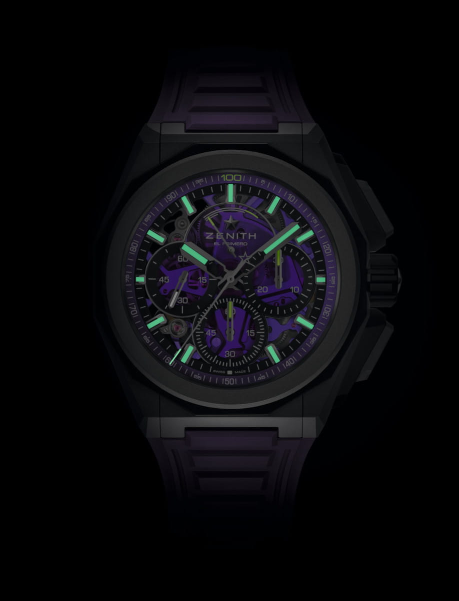 Purple Zenith El Primero skeleton watch with green luminous hands and markers on a dark background.