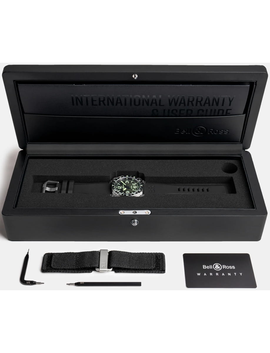 Bell & Ross watch in a black presentation box with foam insert, plus extra strap, tools, and warranty card laid out below.