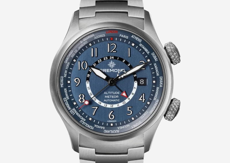 Stainless steel Bremont Altitude Meteor automatic watch with blue dial, multiple world time zones on the bezel, date window at 3 o'clock, and a metal bracelet.
