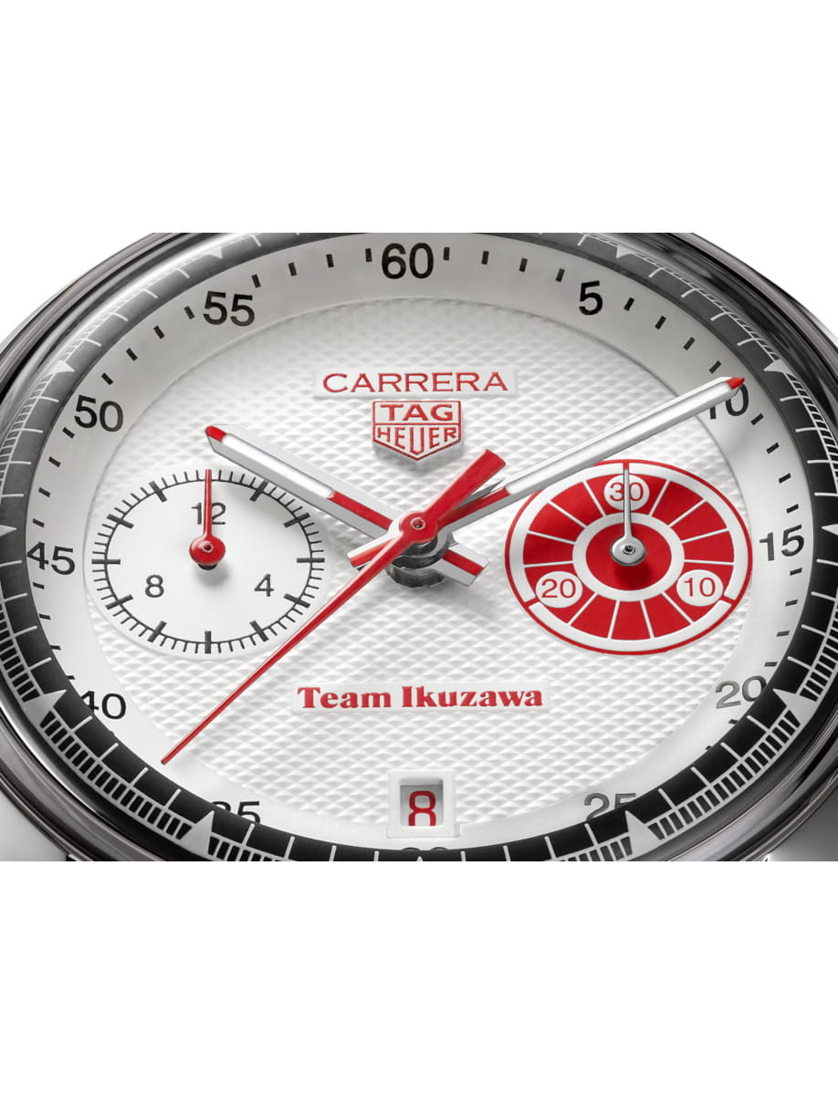 Close-up of a TAG Heuer Carrera watch dial with red accents and 'Team Ikuzawa' text center stage, date window at 6 o'clock.