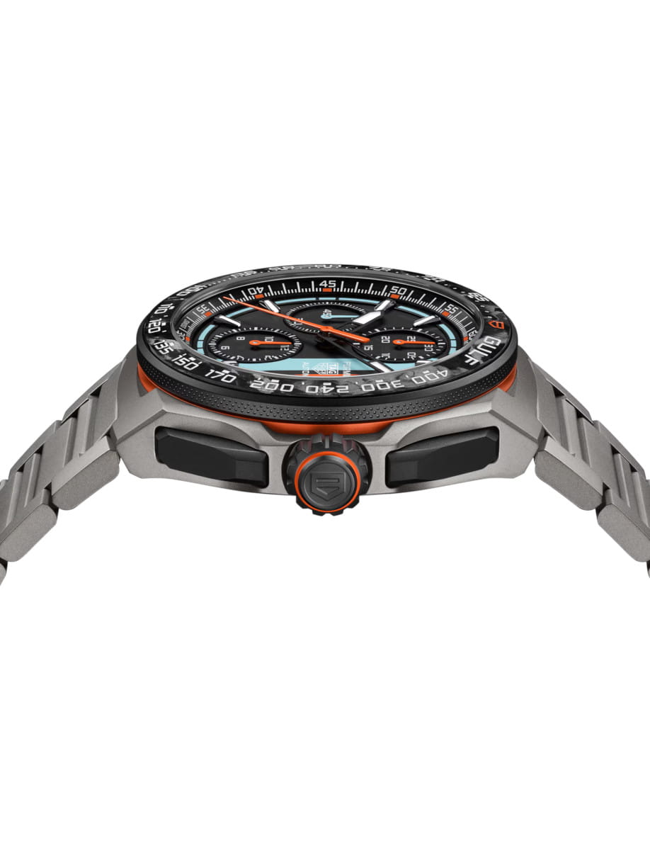Side view of a titanium chronograph watch with orange accents and a textured black bezel on a titanium bracelet