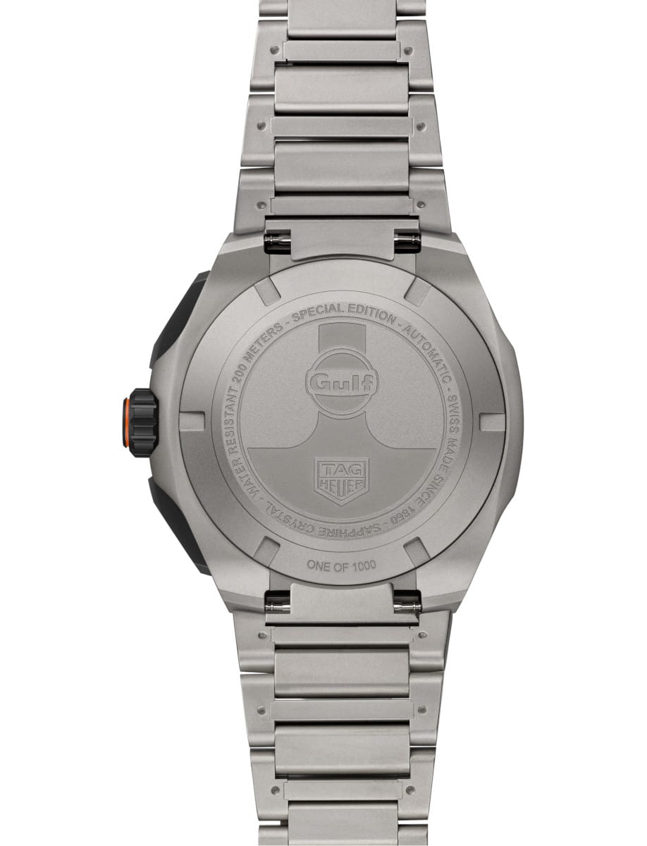 Back of a titanium TAG Heuer watch with an orange crown, showing an engraved case back that reads Special Edition and One of 1000, on a titanium bracelet.