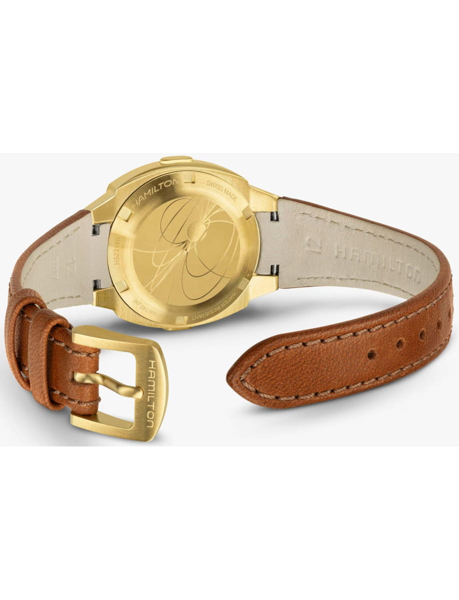 Rear view of a Hamilton wristwatch with a light tan leather strap and a brushed metal case back, showing engravings on the back plate.