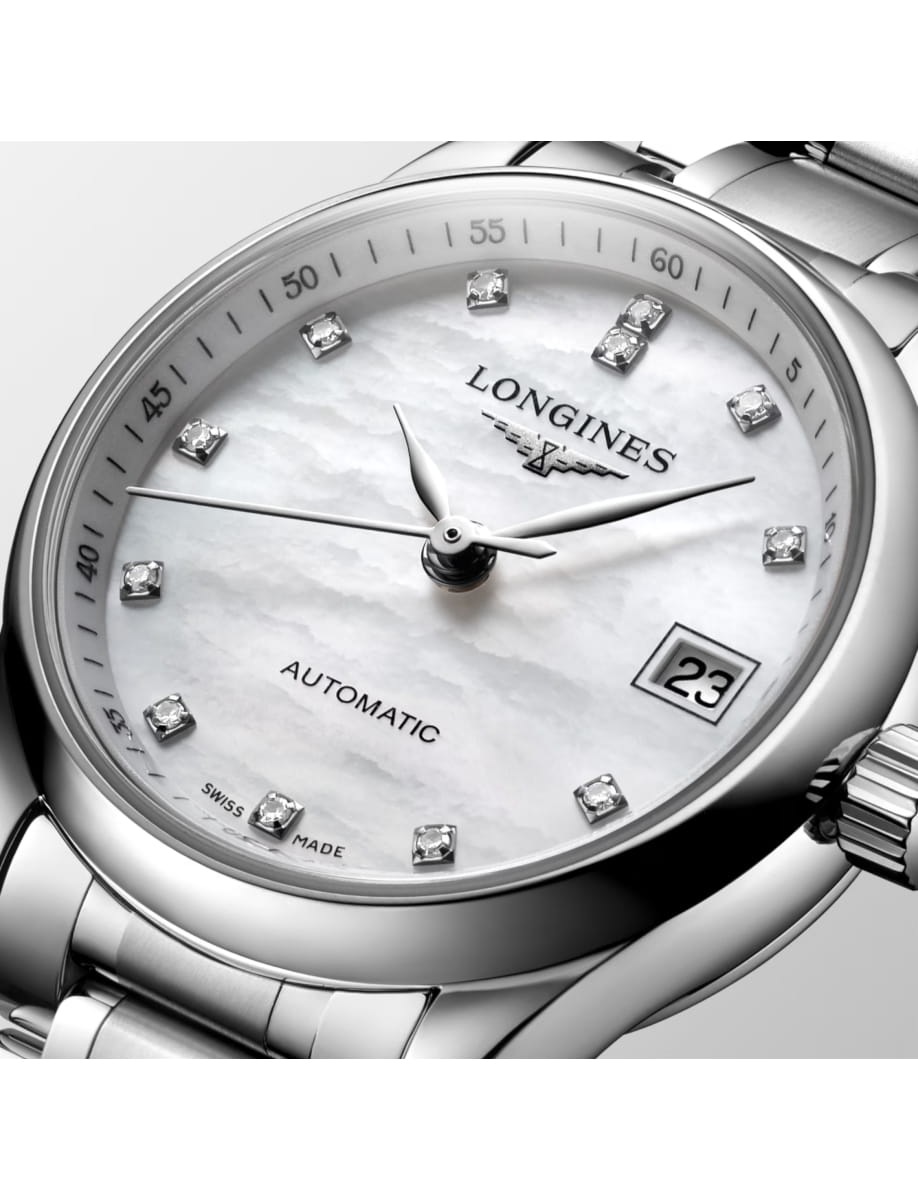 Close-up of a silver Longines automatic wristwatch with diamond hour markers and a date window at 3 o'clock on a white dial.