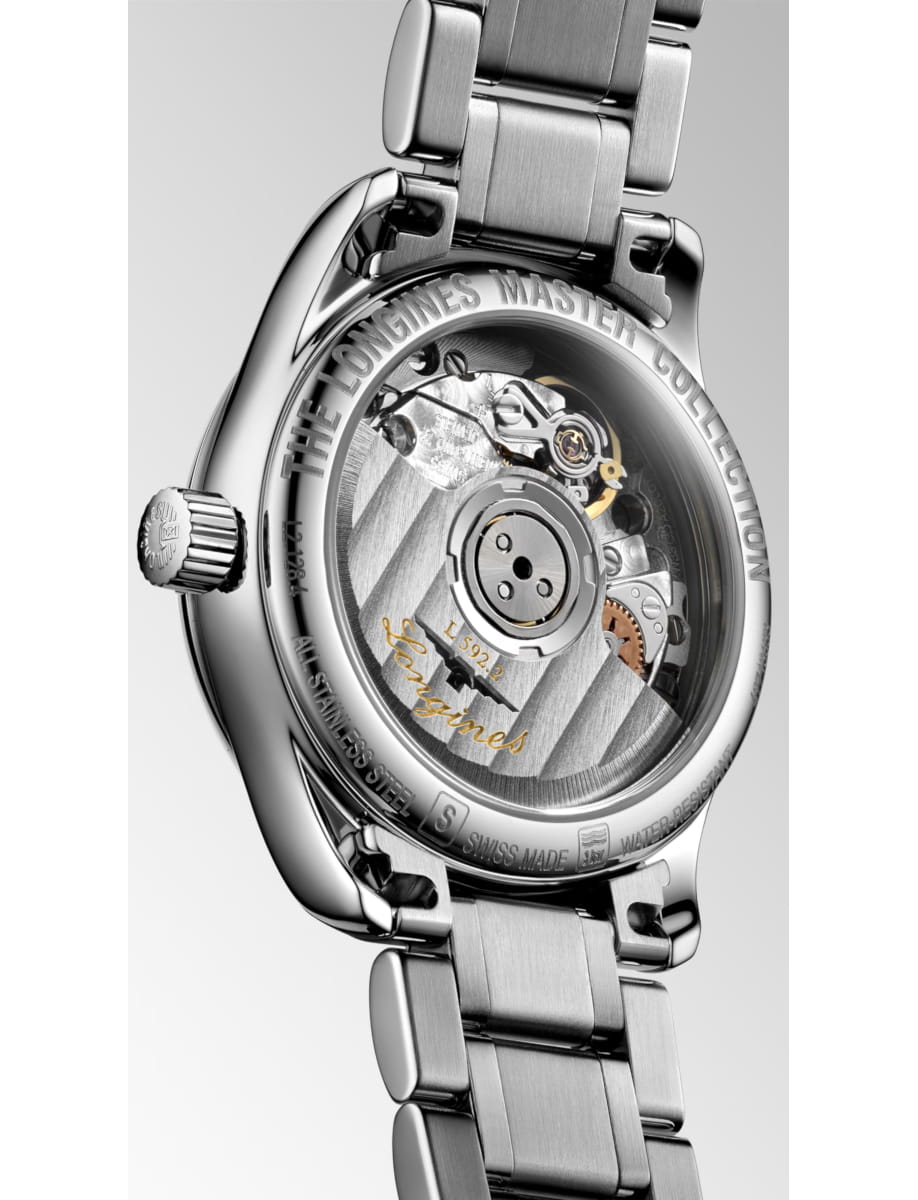 Stainless steel watch back with a transparent case revealing its mechanical movement and engravings like 'Longines Master Collection' and gold cursive signature on a silver bracelet.