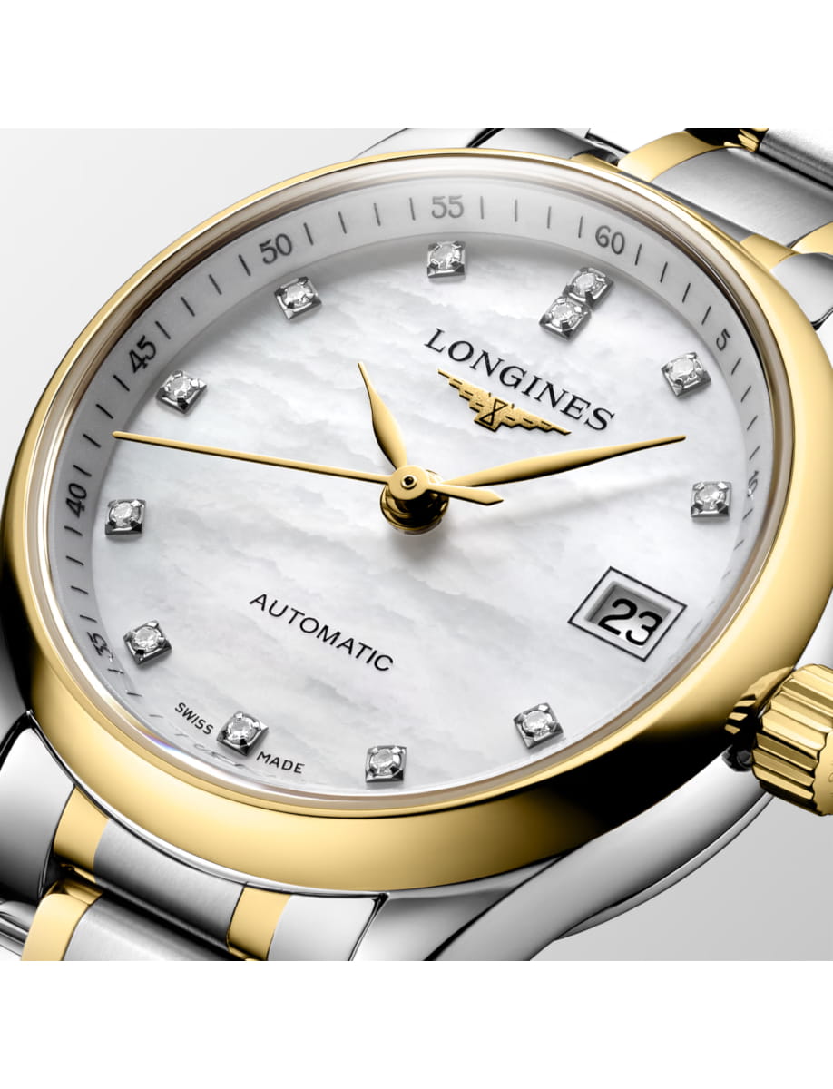 Close-up of a two-tone Longines wristwatch with diamond hour markers, white marble dial, gold hands, and a date