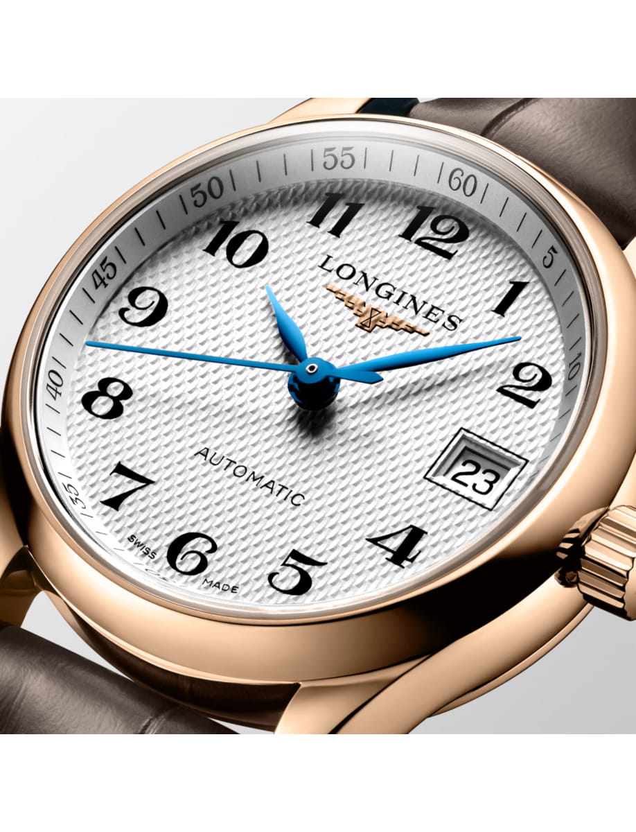 Close-up of a gold Longines automatic wristwatch with blue hands and a date window