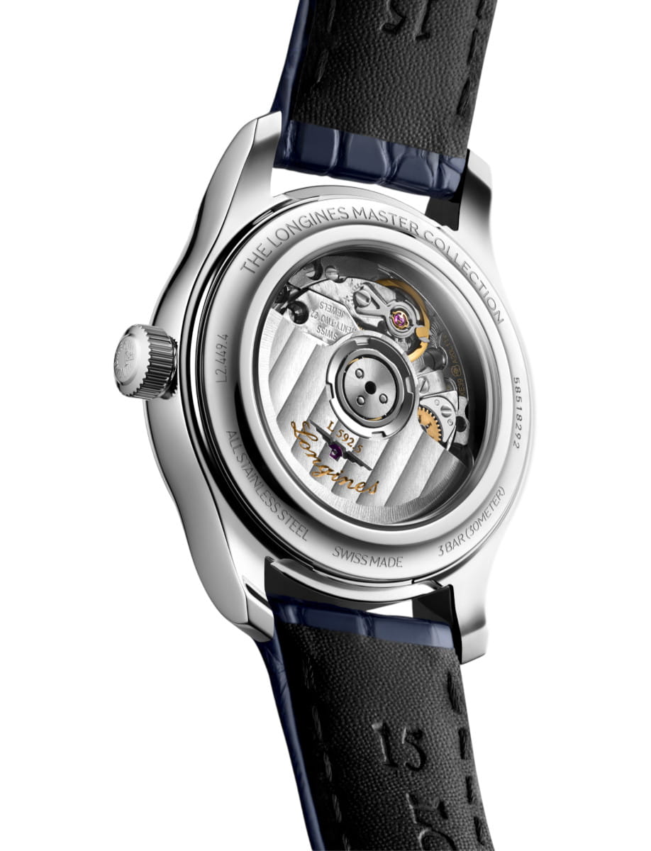 Back of a stainless steel watch showing an exposed mechanical movement through a transparent caseback, engraved with The Longines Master Collection and Swiss Made with a blue leather strap visible.