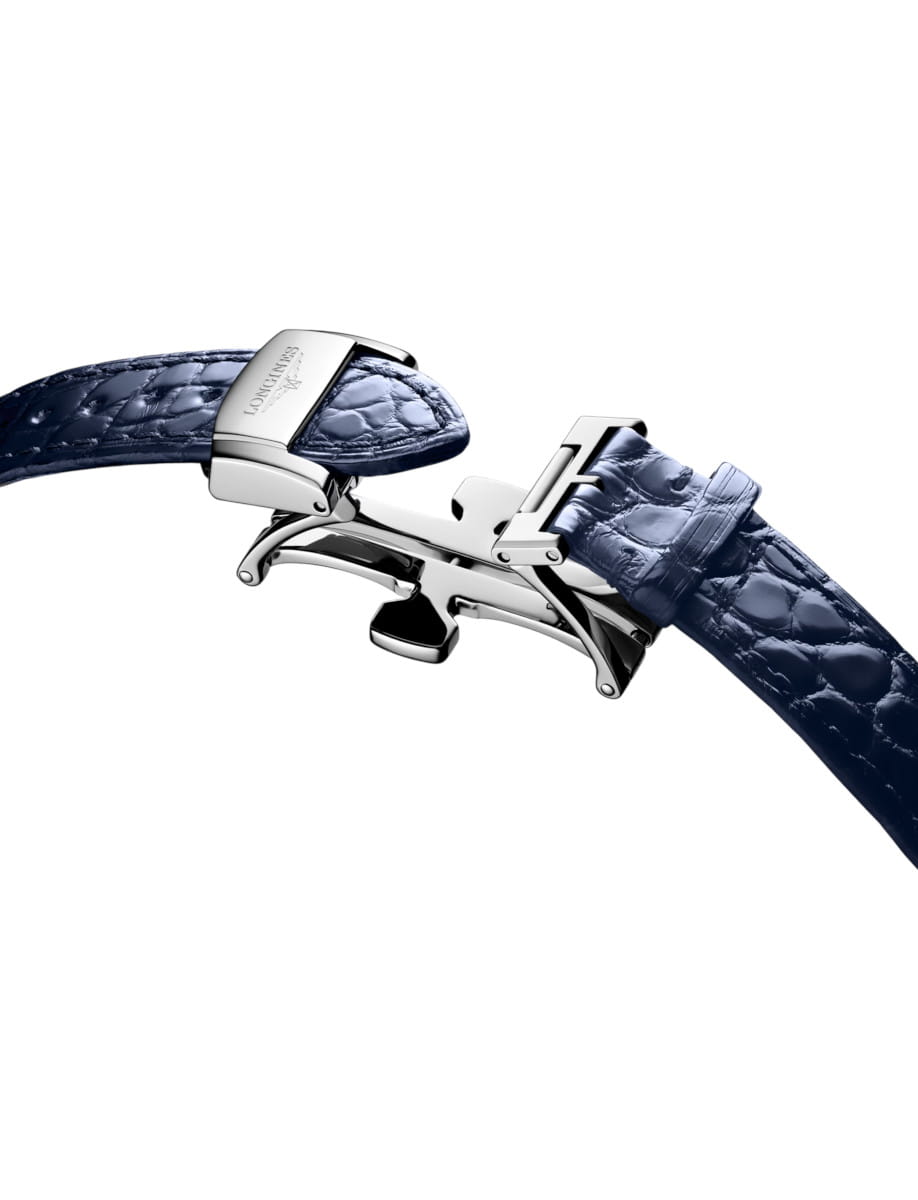 Close-up of a polished steel deployant clasp on a blue alligator leather watch strap.
