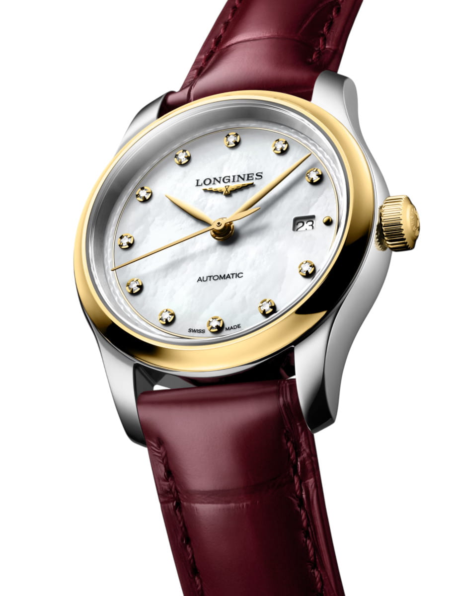 Close-up of a stainless steel watch back showing the mechanical movement with a yekllow-gold rotor and engraved text, bordeaux-black leather strap visible behind the case