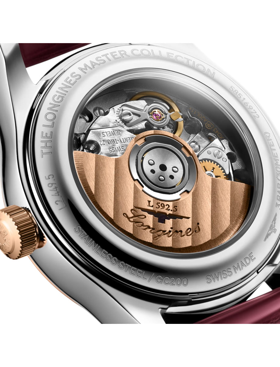 Close-up of a luxury watch caseback showing the automatic movement with a gold rotor and visible gears, engraved markings, and Swiss craftsmanship.