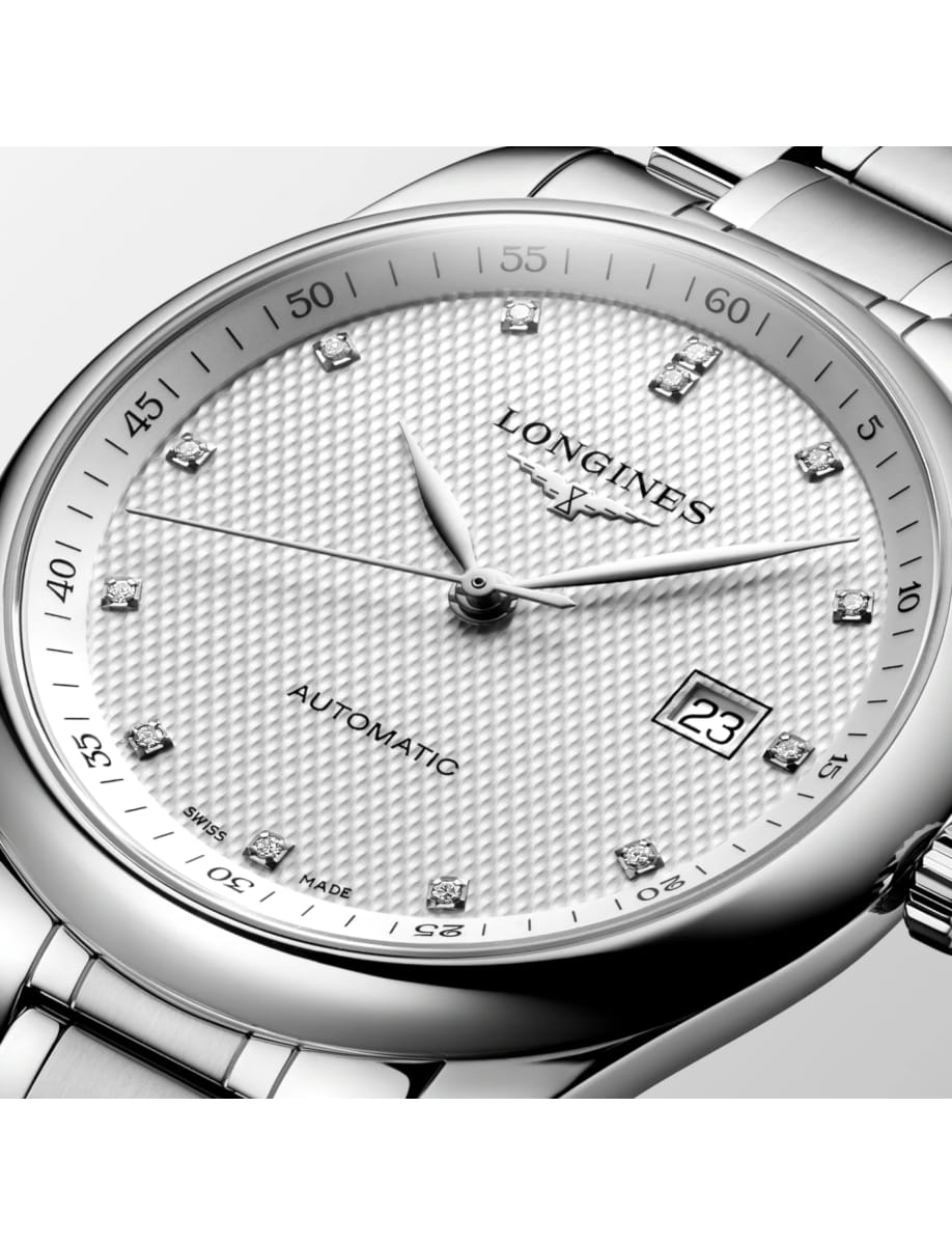 Close-up of a silver Longines automatic wristwatch with diamond hour markers and a date window showing 23 at 3 o'clock, on a textured dial.