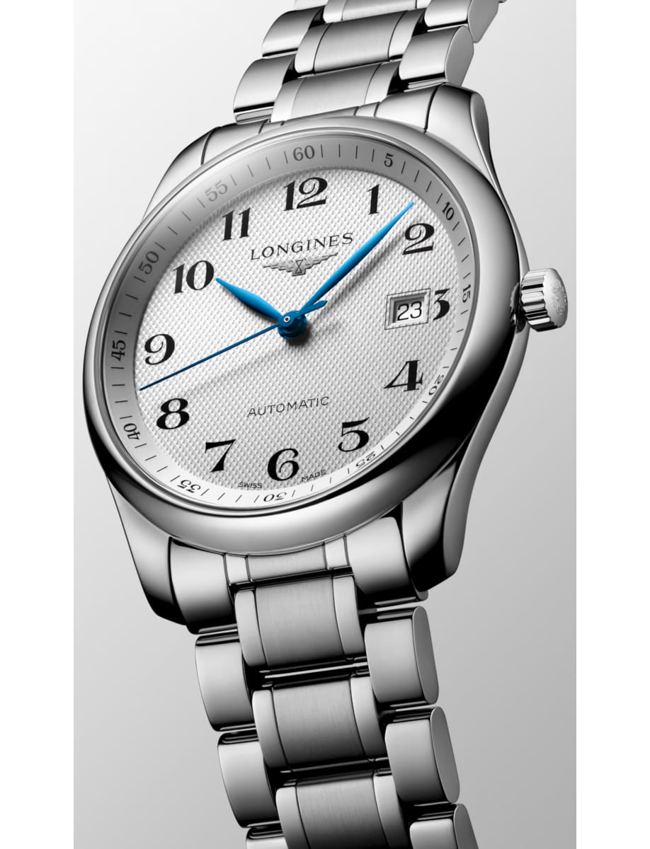 Close-up of a stainless steel Longines automatic wristwatch with blue hands, black numerals, and a date window at 3 o'clock.