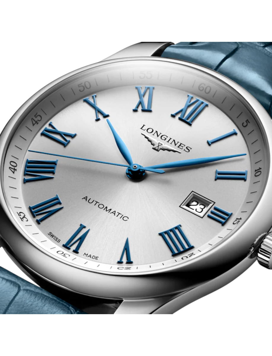 Close-up of a Longines automatic wristwatch with blue Roman numerals, silver dial, and a date window showing 23 on the right edge.