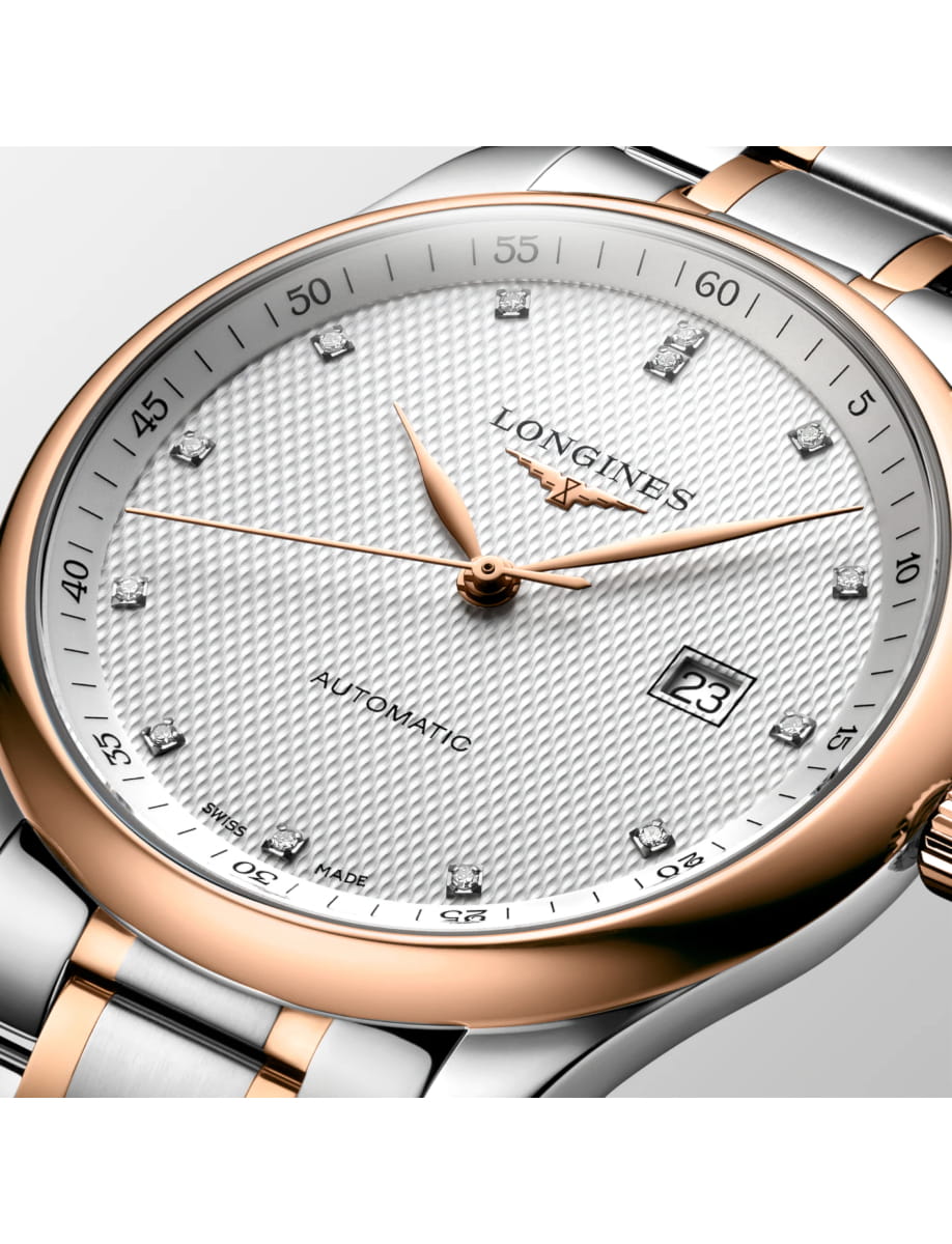 Close-up of a two-tone Longines automatic wristwatch with a textured white dial, diamond hour markers, rose-gold hands, and a date window at 3 o'clock