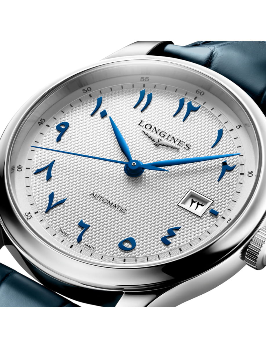 Close-up of a steel Longines automatic watch with blue stylized numerals, textured dial, and date window.