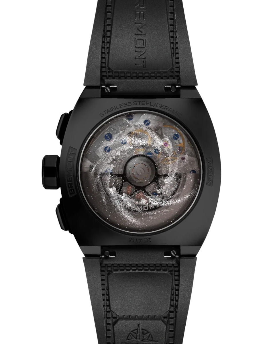 Black Bremont watch shown from the back, with a transparent case back revealing the inner gears and rotor; black strap with visible stitching.