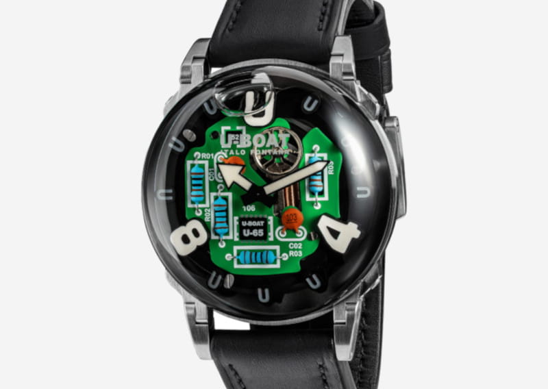 Wristwatch with a visible green circuit-board face and large white numerals, black leather strap, silver case.