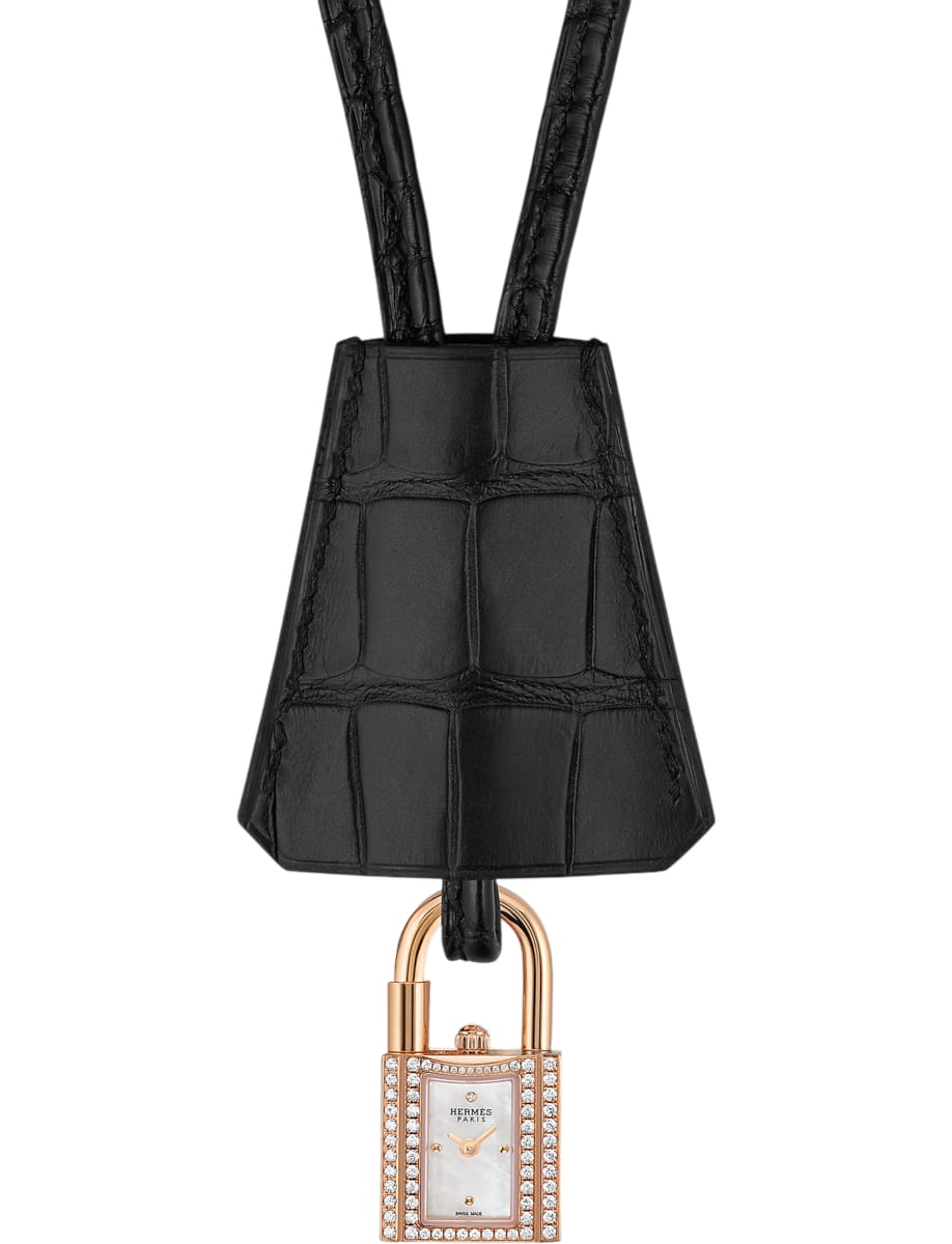Gold-tone rectangular Hermès watch with diamond bezel hanging from a black crocodile-embossed strap or charm attachment.