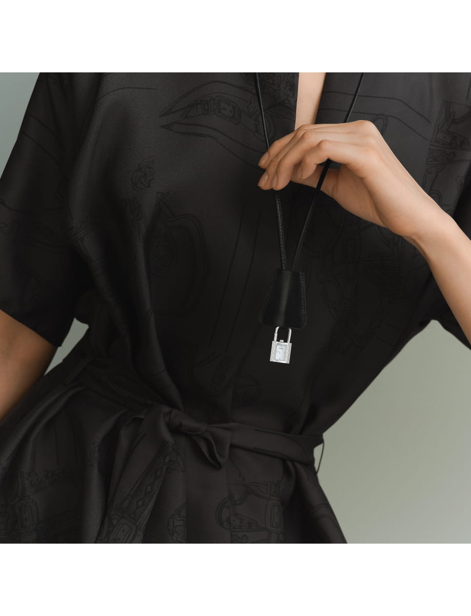 Close-up of a black outfit with a silver padlock necklace hanging from a black cord.